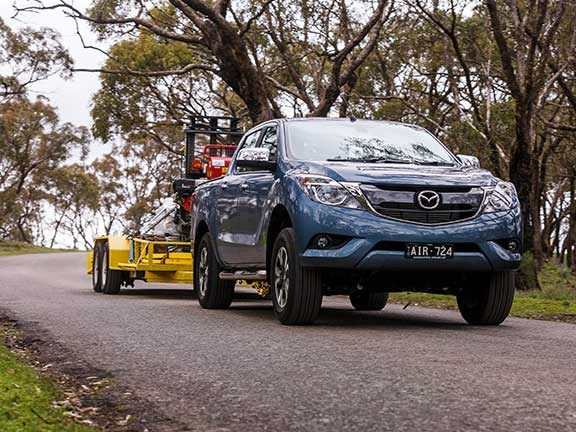 Mazda BT-50 towing excavator downhill