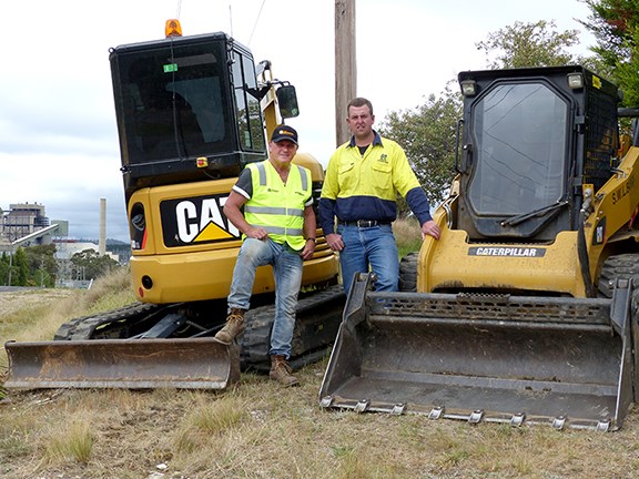 Ron Horner and Andy Sheather with the Cat excavator/skid steer combo and Wallerawang Power Station in the background.