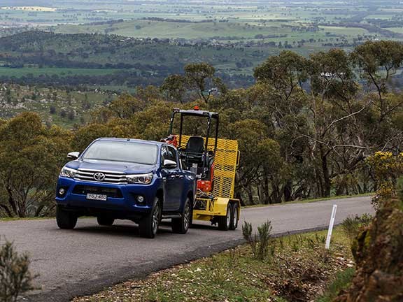 Toyota Hilux ute towing excavator on trailer